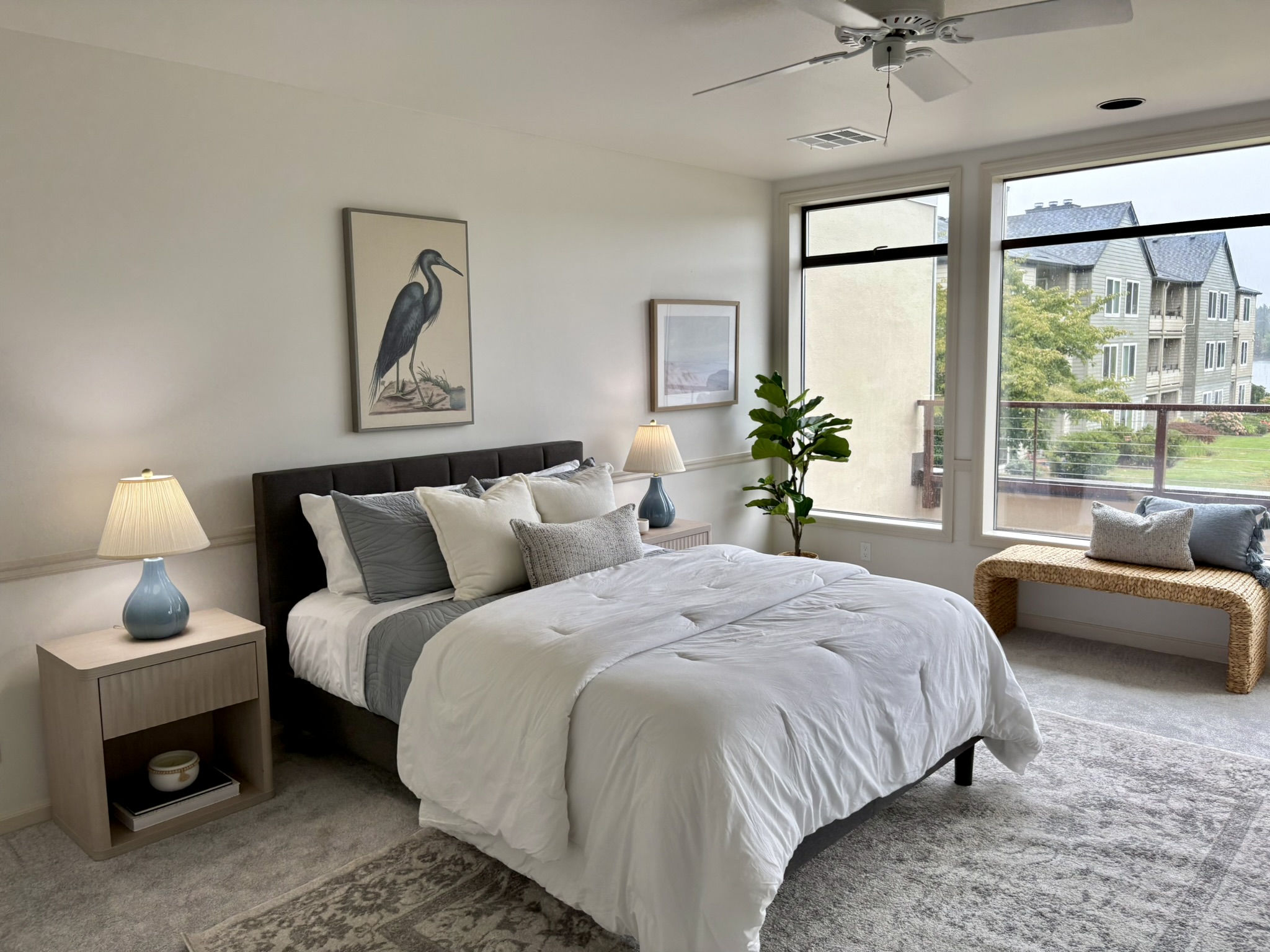 Bedroom with upholstered bed, blue bedside lamps and river-facing windows