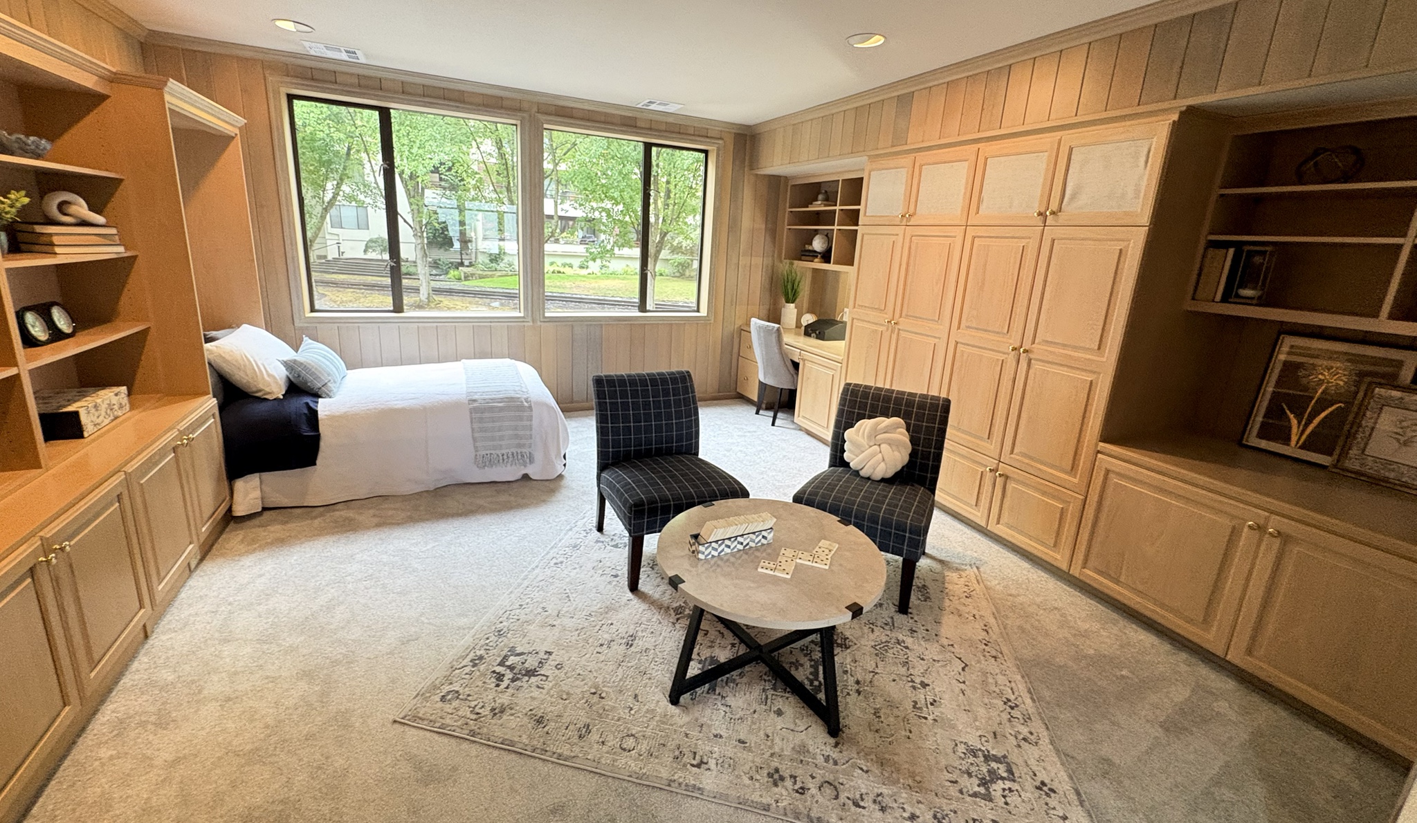 Wide view of the wood-paneled den with daybed, plaid chairs and built-in desk