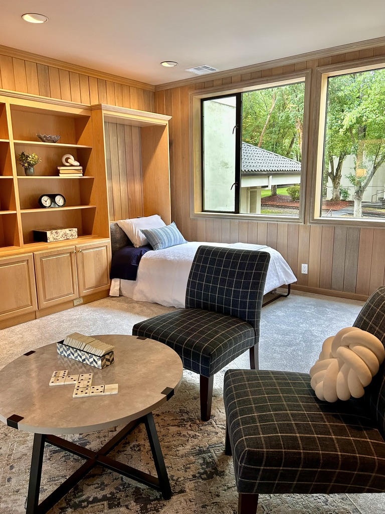 Wood-paneled den with daybed, plaid chairs and game table