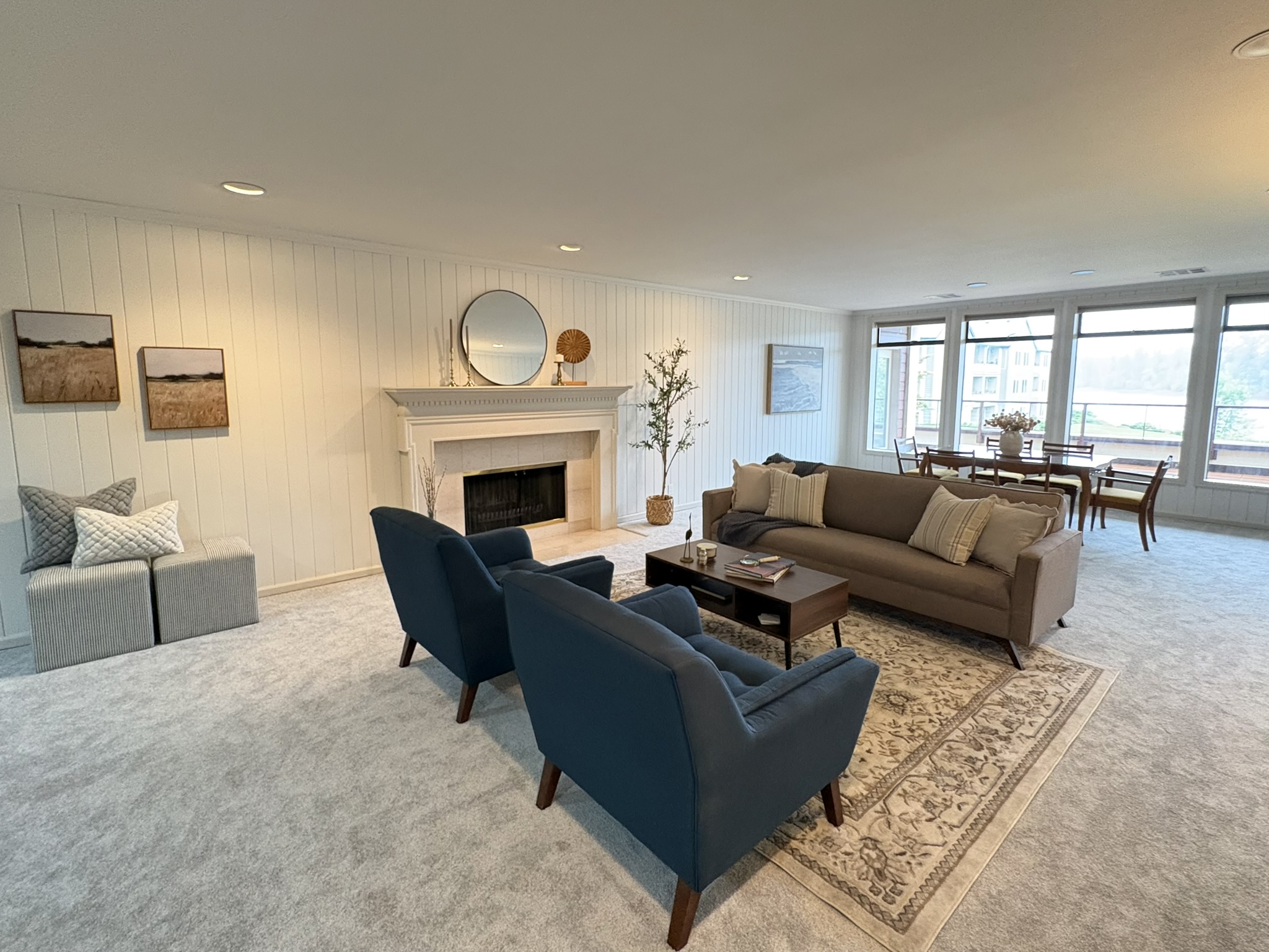 Living room with fireplace, blue armchairs and adjoining dining area
