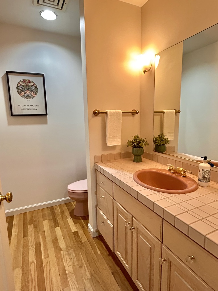 Powder room with terracotta basin, tiled vanity and wood floor