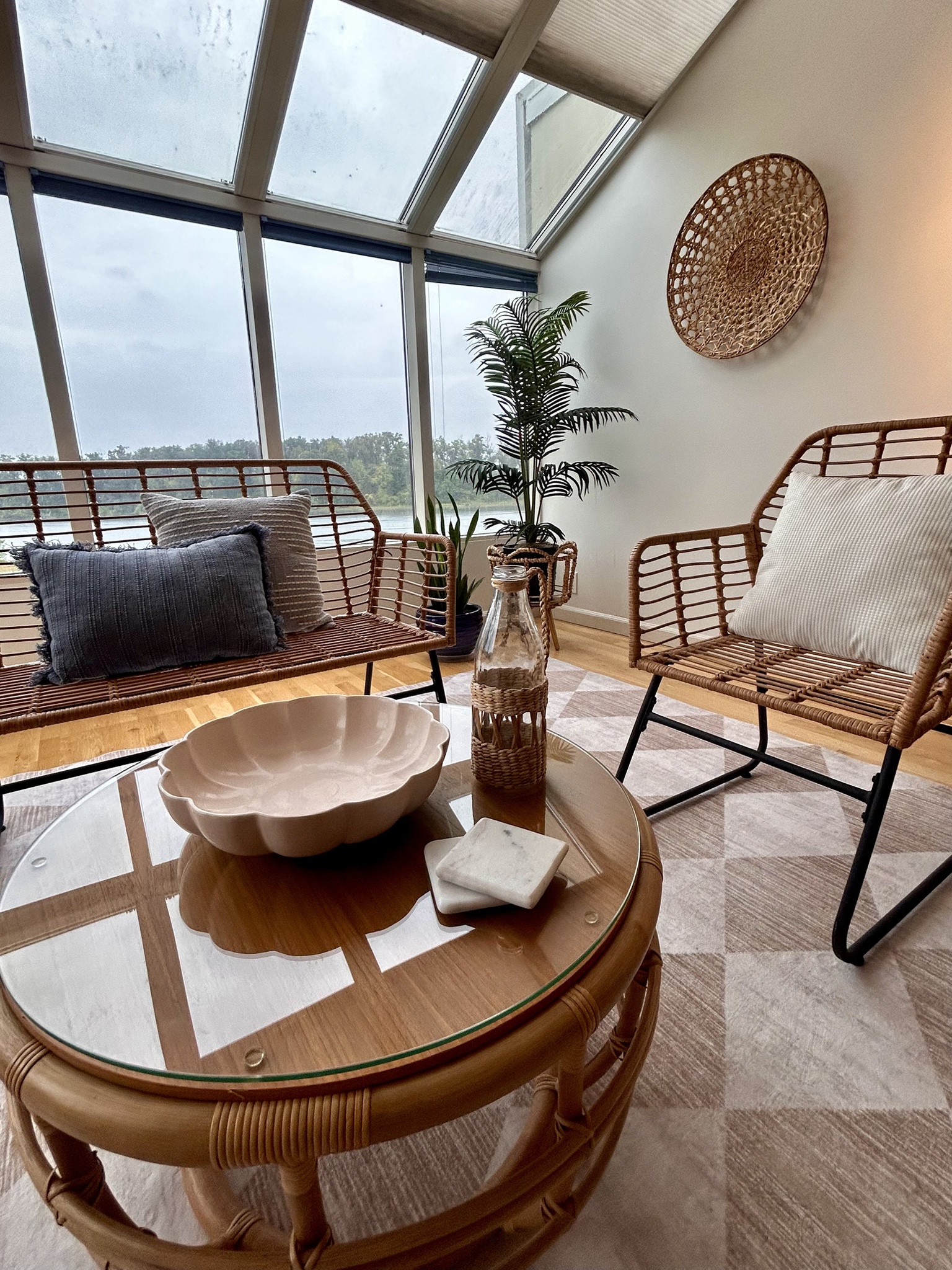 Sunroom wicker seating, layered pillows and round glass table
