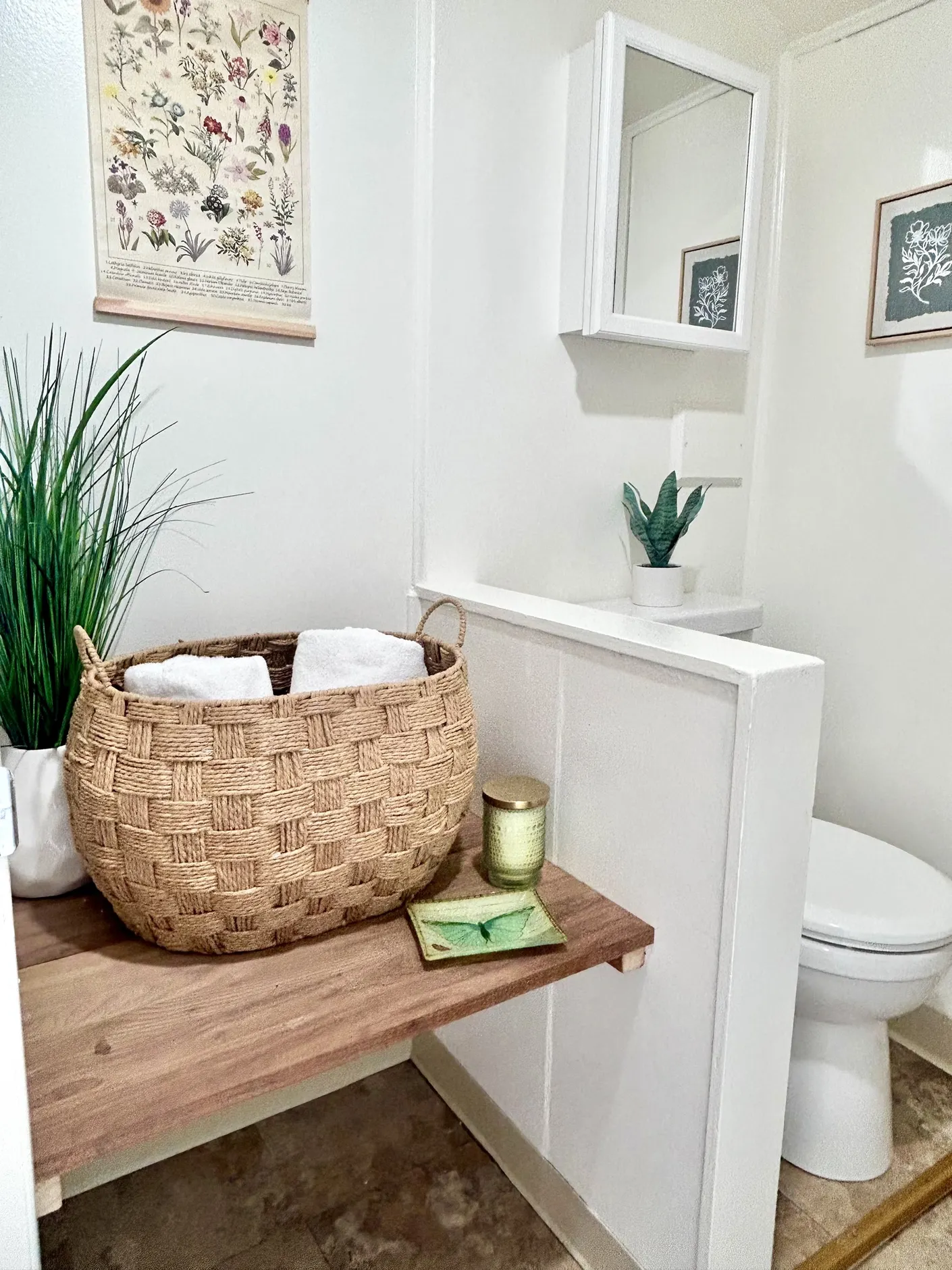 Bathroom styled with woven basket, towels, and botanical art