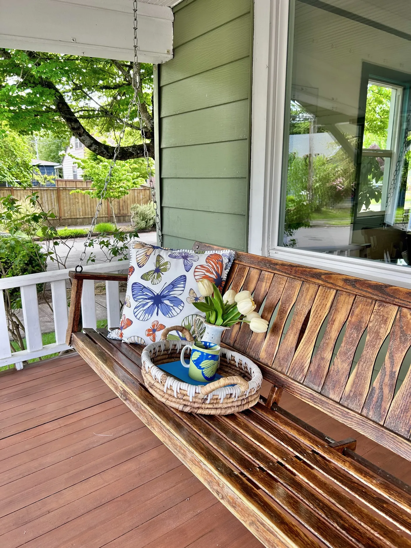 Front porch bench with floral pillow and potted tulips