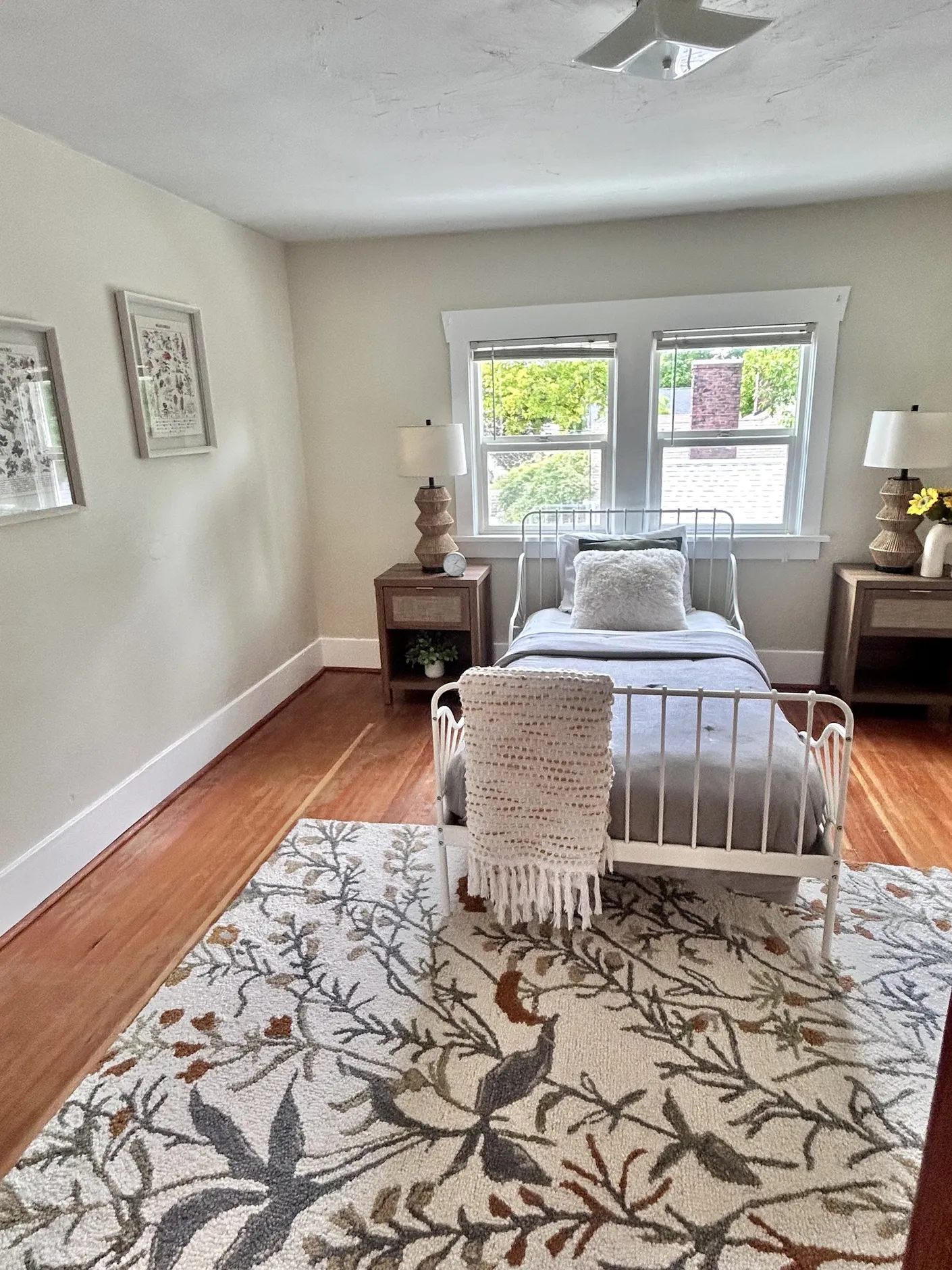 Guest bedroom with white metal bed and patterned rug