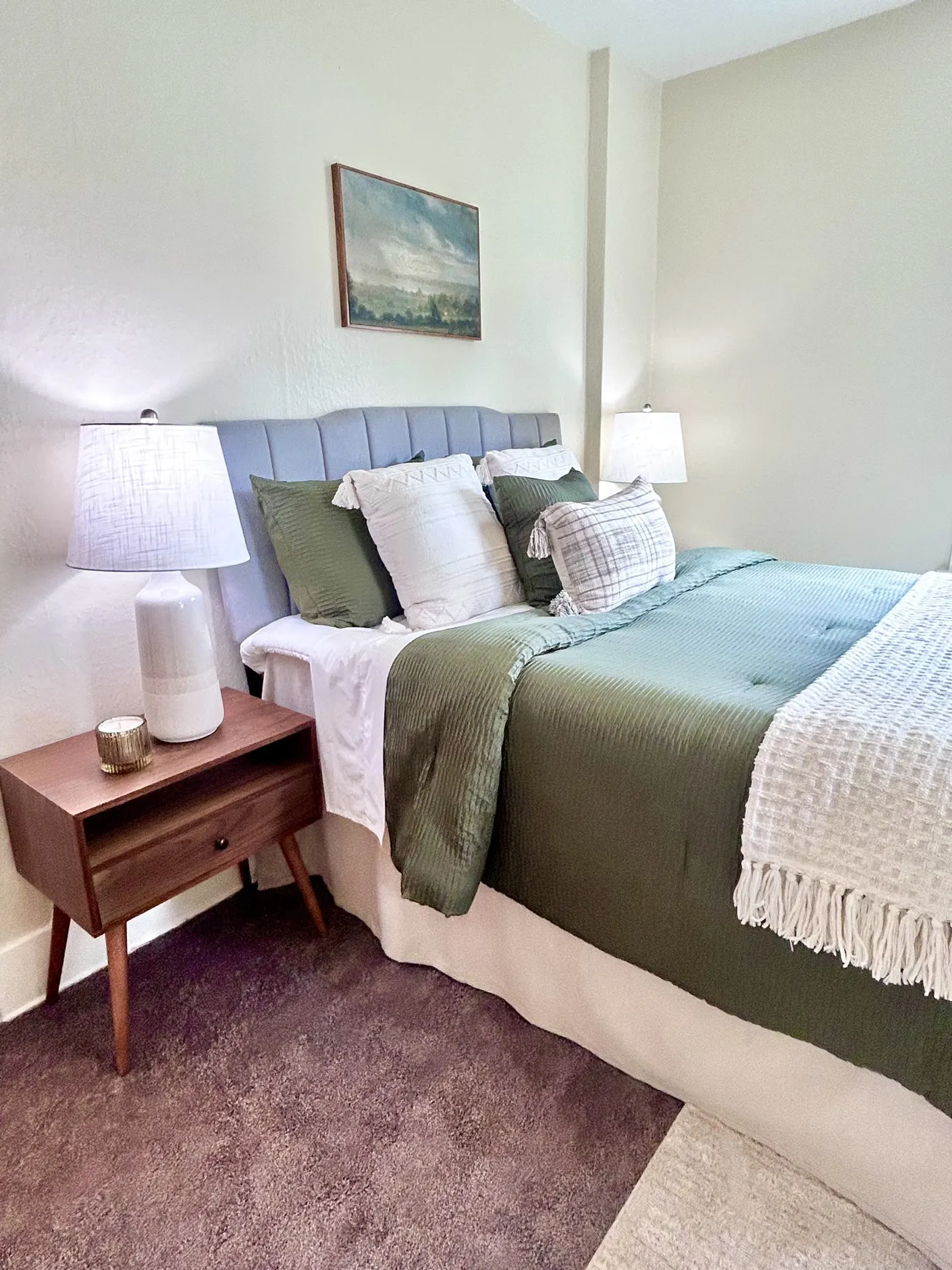 Bedroom with dark green bedding and midcentury nightstand
