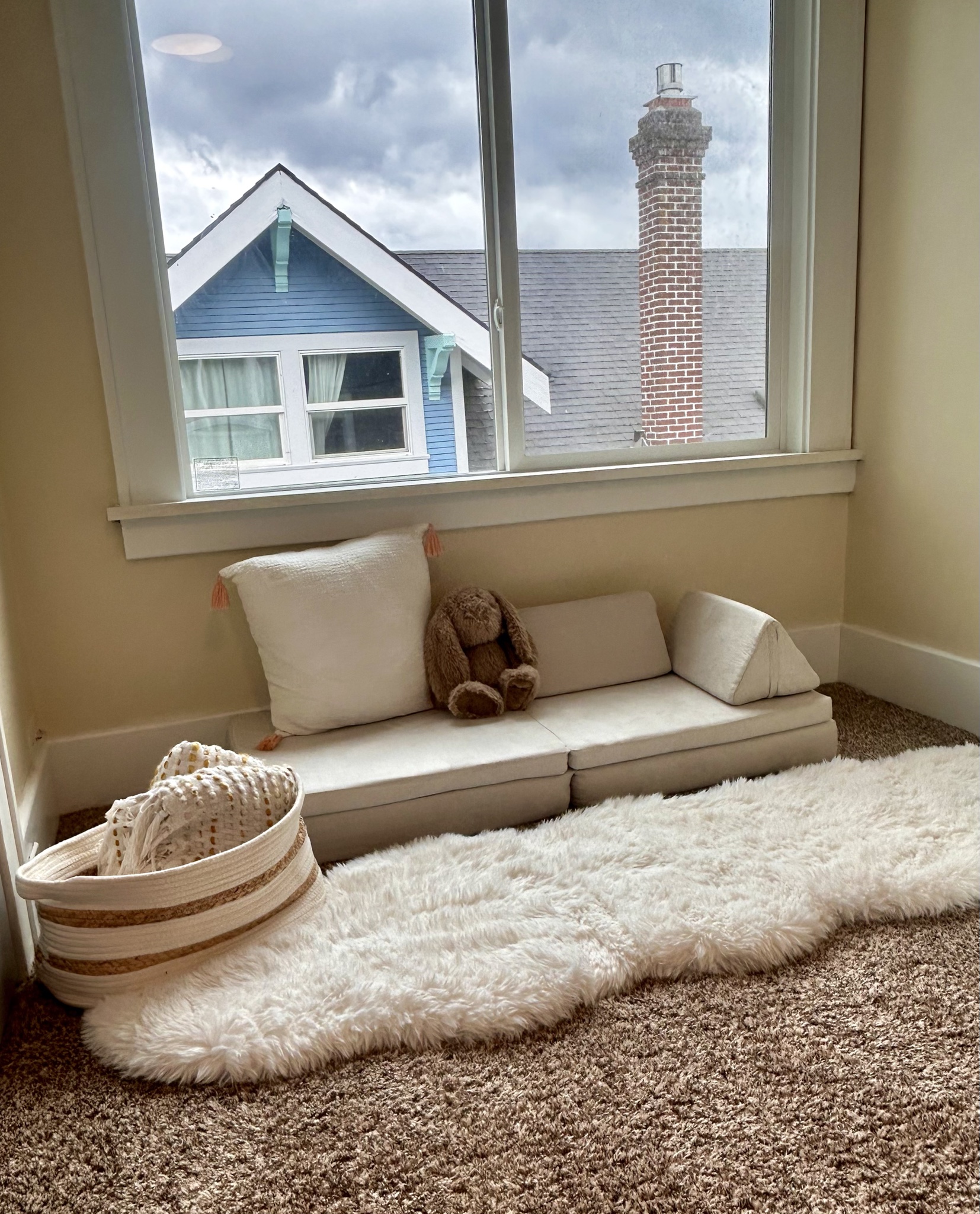 Children’s reading nook with a small cream sofa and soft rug