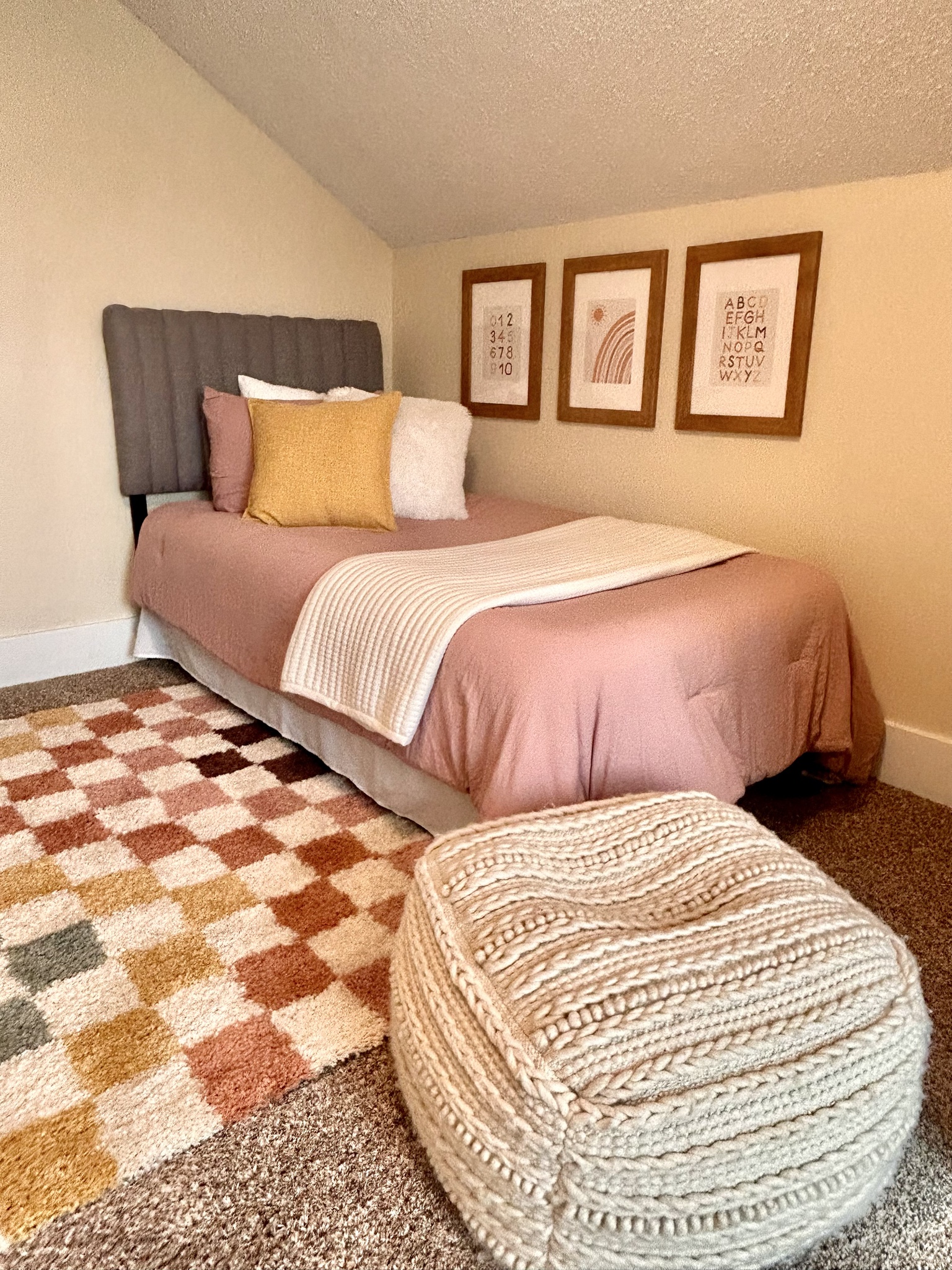 Bedroom with rose-colored bedding and a checked rug