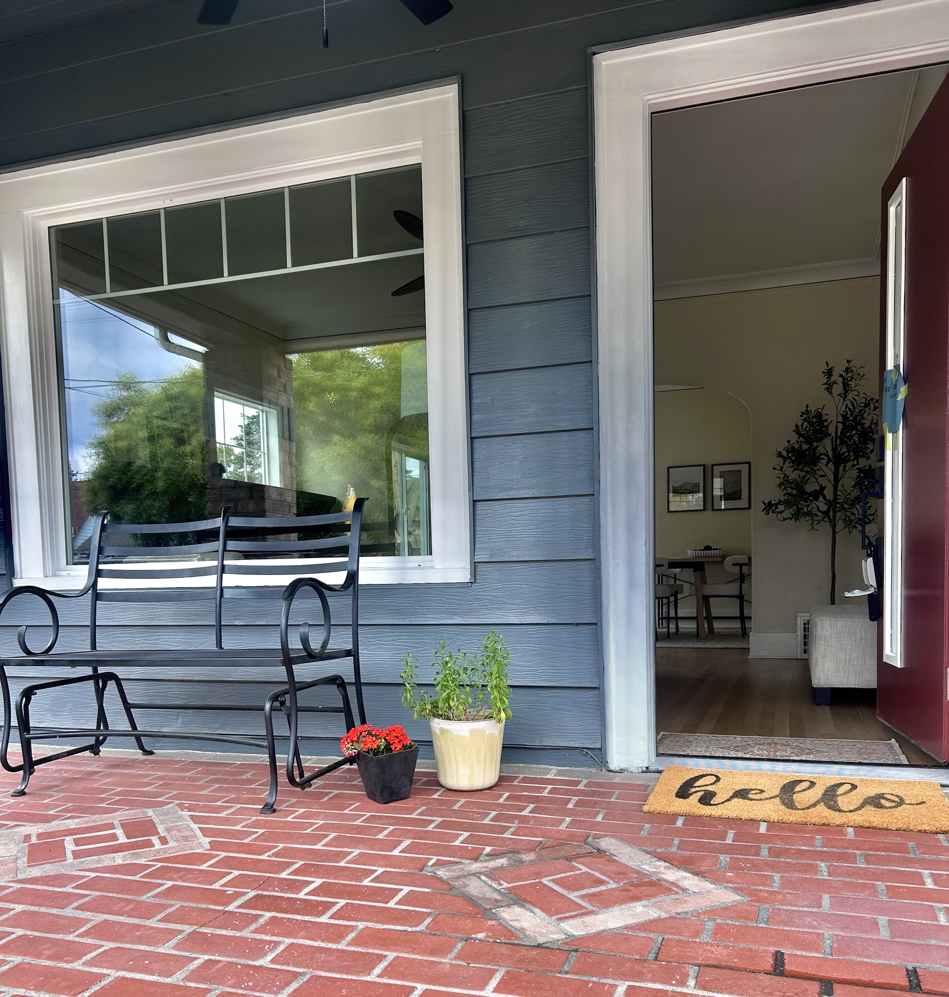 Front porch with blue siding, brick floor and a welcoming doormat