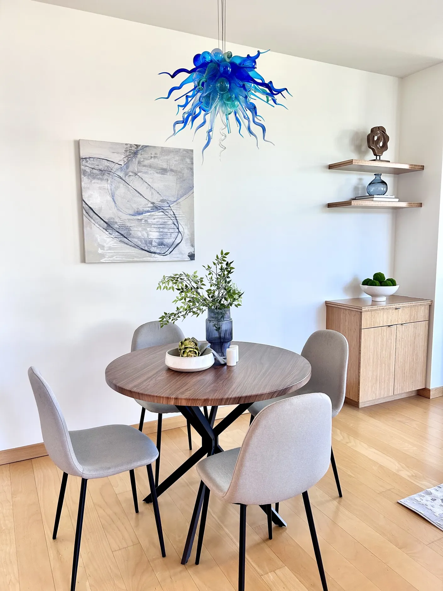 Round dining table beneath a blue glass pendant