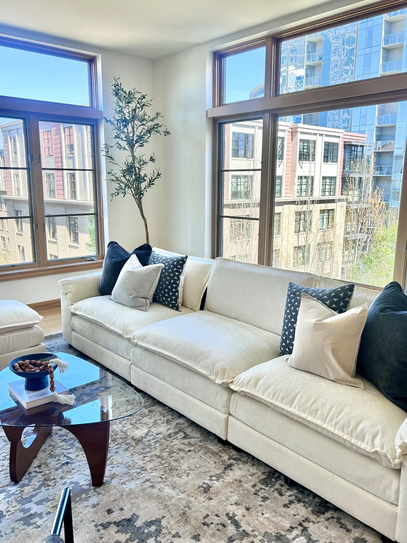 White sofa with blue pillows beside tall Pearl District windows