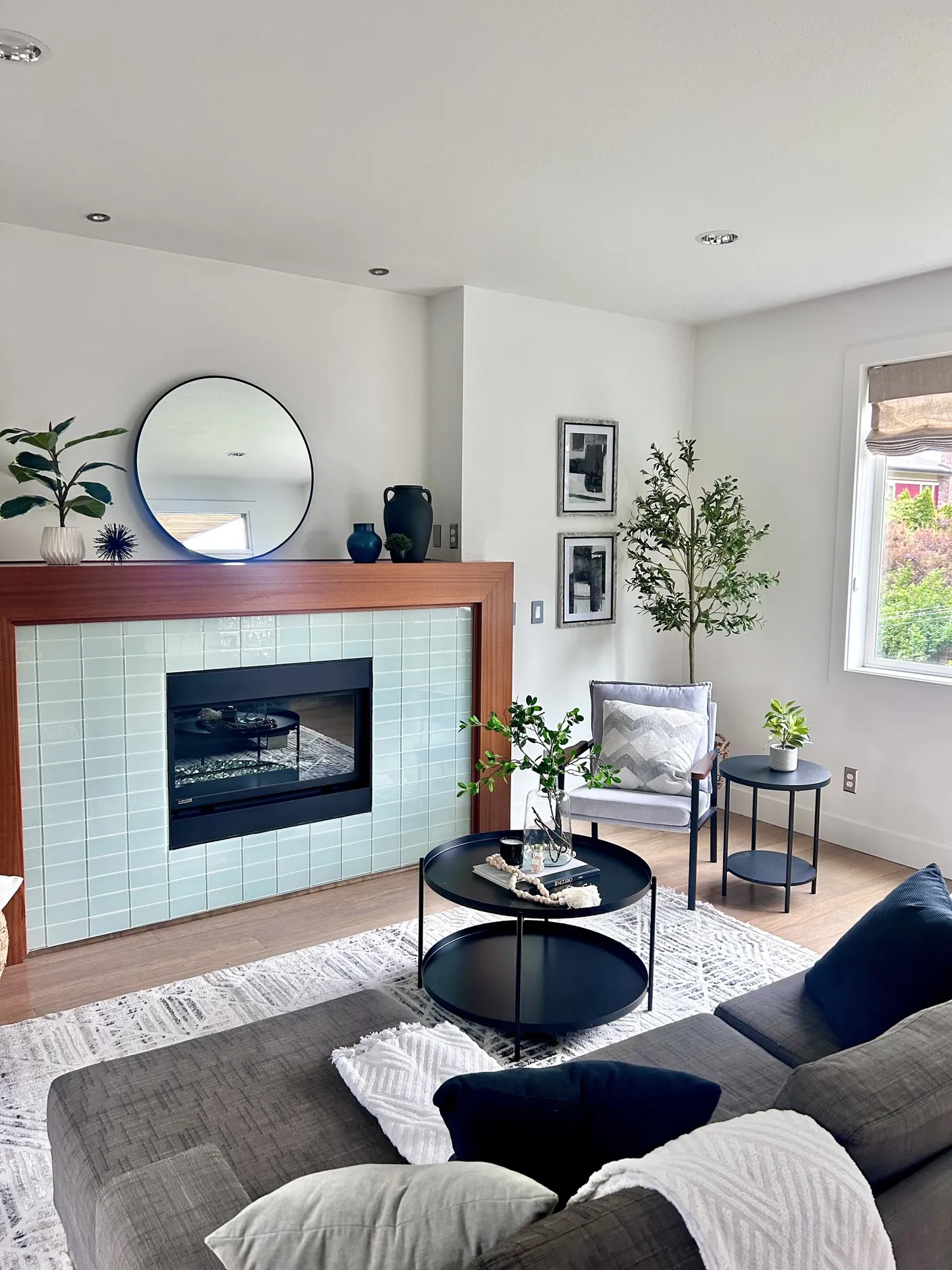 Living room with tiled fireplace, gray sofa, and layered accents