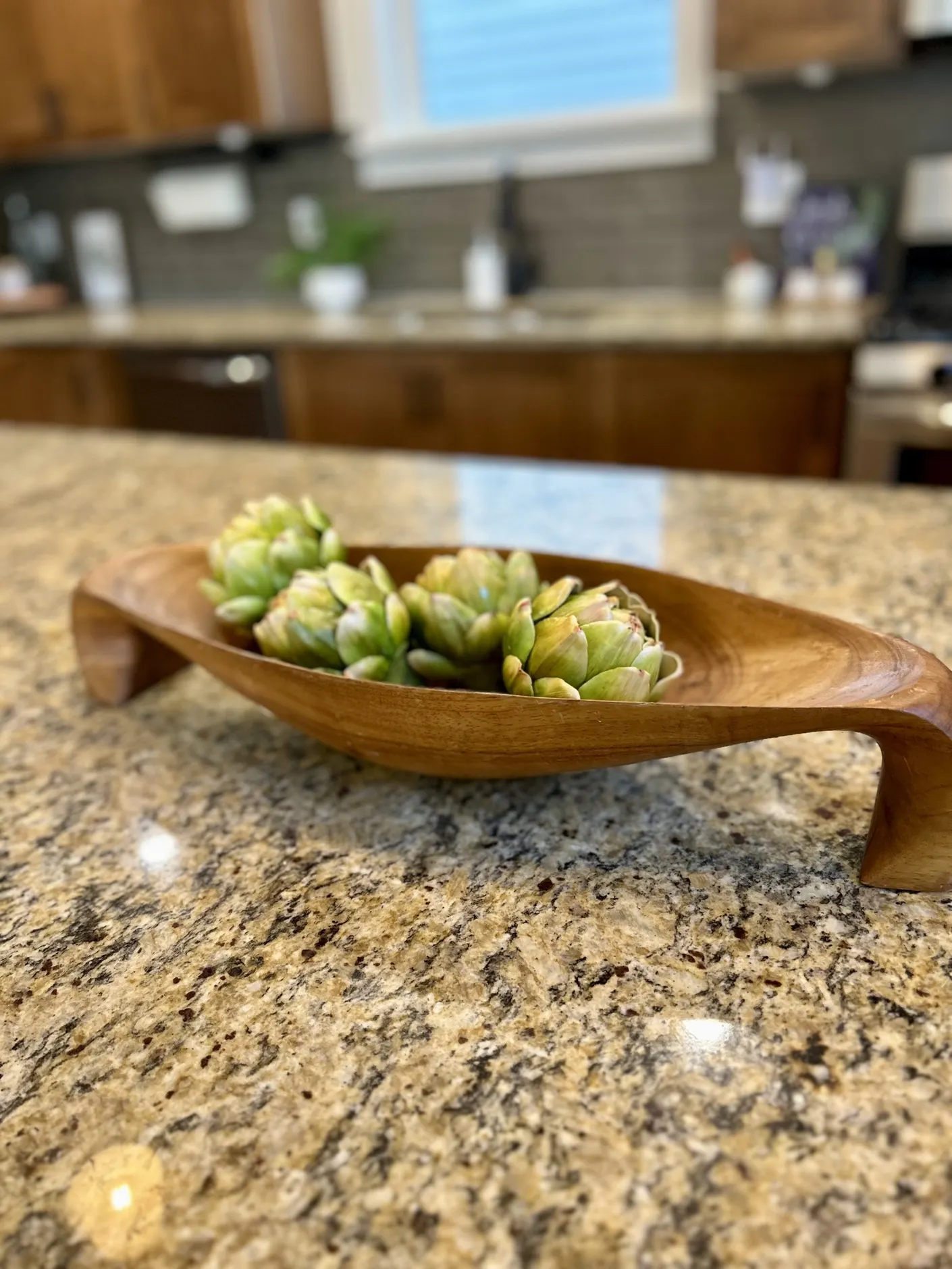 Wooden bowl of artichokes on the kitchen counter