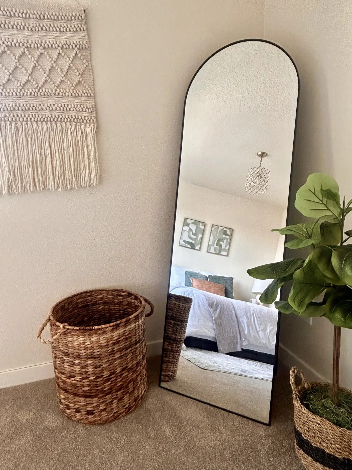 Arched mirror reflecting a staged bedroom