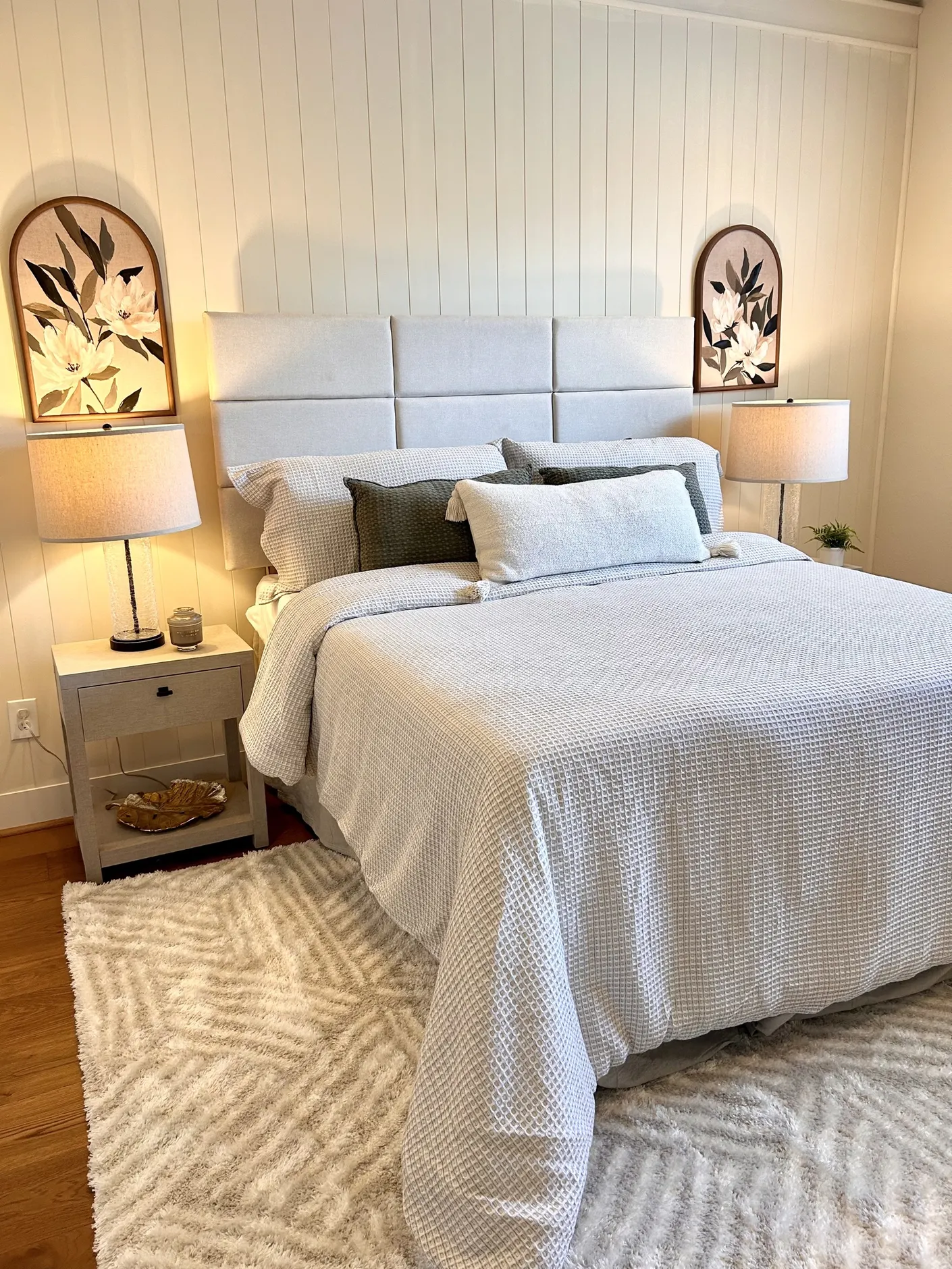 Bedroom with paneled wall and floral artwork